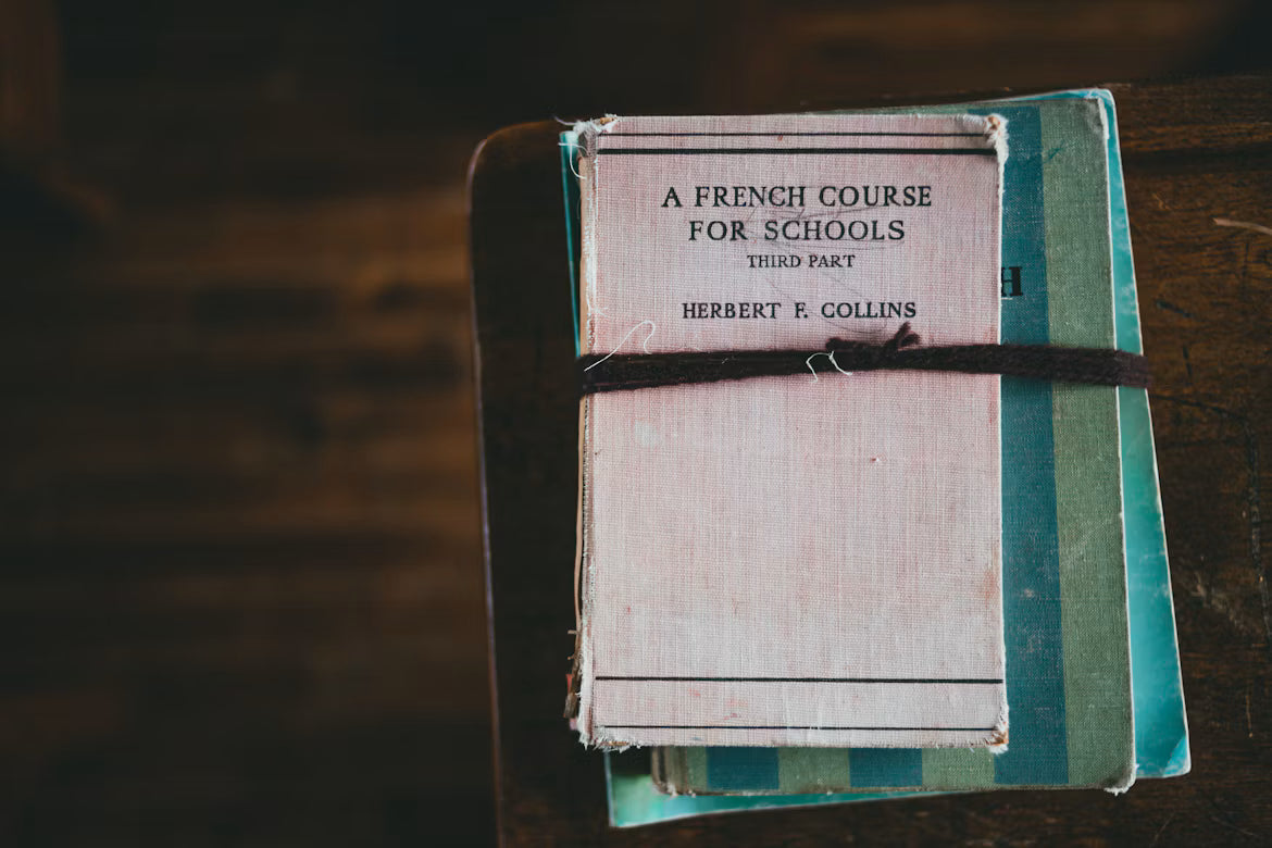 A worn French course book tied with a strap on a wooden table